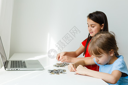 两个孩子一起数硬币休闲女孩教育女性数数童年瓶子手臂喜悦男性图片