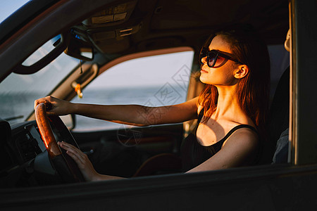 以时装旅行方式驾驶汽车的妇女太阳镜女性敞篷车车辆车轮女孩交通乘客阳光镜子图片