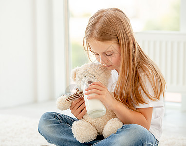 可爱的小女孩玩泰迪熊青年拥抱幸福快乐动物乐趣眼睛喜悦女士牛奶图片