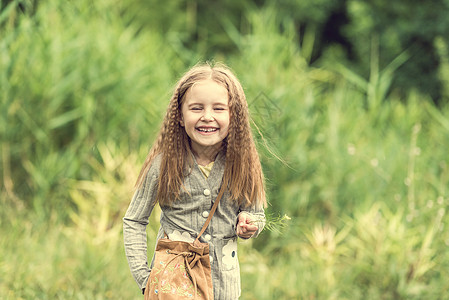 可爱的小女孩在夏天走路头发花园日落乐趣晴天女性公园阳光草地花朵图片