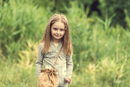可爱的小女孩在夏天走路头发乐趣日落幸福花园太阳花朵天空阳光公园图片