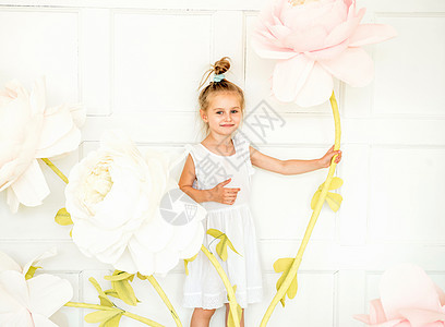 小女孩在演唱室装饰的对面工作室里摆着人造花朵乐趣快乐裙子幸福艺术女性白色童年头发魔法图片