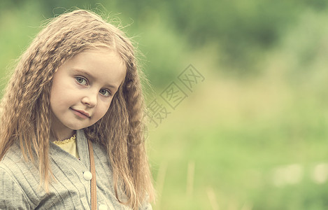 可爱的小女孩在夏天走路场地花园花朵阳光乐趣头发女性草地晴天快乐图片