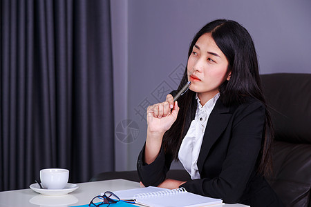 坐在办公桌旁并思考工作的女性商业女商务人士写作窗户套装眼镜百叶窗窗帘人士成人商务女孩图片