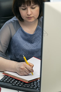 年轻女性在工作场所用笔记本写作 工作秘籍 任务经理 日程安排任务图片