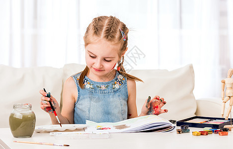 小女孩用水彩的草地艺术家女孩享受桌子绘画孩子艺术幼儿园快乐情感图片