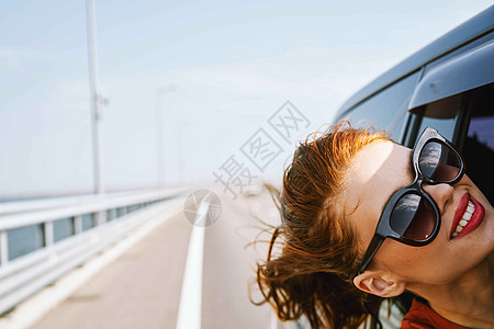 身戴墨镜的妇女在汽车窗外看望着的车窗 旅行生活方式自由太阳女士蓝色潮人太阳镜家庭假期司机女孩图片