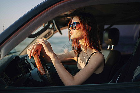 穿着太阳眼镜的漂亮女人 驾车出行商业乘客魅力车辆奢华汽车阳光交通微笑女孩图片