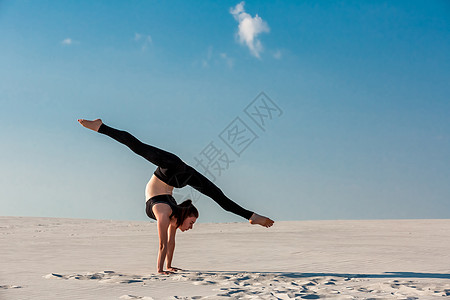 年轻女子在沙滩上用白沙和明蓝的天空打手架冥想呼吸运动保健运动员假期反转冒充练习沉思图片