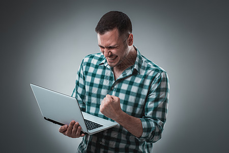 有吸引力的商务人士模特身着绿色衬衫 与灰色隔绝 用笔记本电脑工作 用左手显示一些东西学生互联网办公室成人写作人士男人情绪商务技术图片