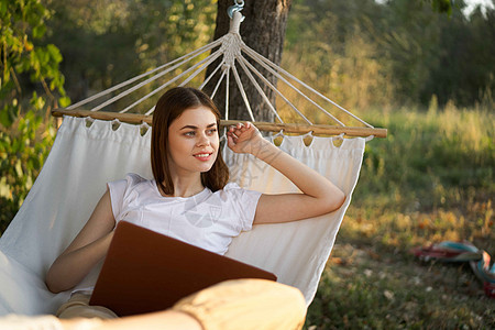 快乐的女人躺在吊床里 带着笔记本电脑度假的互联网旅行享受花园假期上网阅读女性海滩女孩丛林热带图片