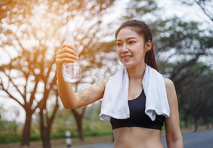 年轻运动女青年 公园里有一瓶水毛巾女性闲暇花园湿巾女士身体训练运动装棉布图片