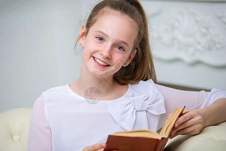 一个可爱的小女孩坐在沙发上 热情地阅读一本书婴儿女孩微笑智力学习幼儿园女学生家庭快乐情感图片