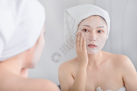 妇女脸上戴面罩 照镜子她们用面具遮着脸 看着镜子女孩肤色奶油温泉浴室反射化妆品清洁护理毛巾图片