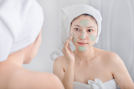 妇女脸上戴面罩 照镜子她们用面具遮着脸 看着镜子治疗清洁毛巾女孩奶油浴室女性肤色温泉黏土图片