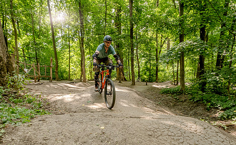 男子在森林道路上骑自行车冒险阳光速度乐趣公园锻炼头盔骑术骑士踪迹图片