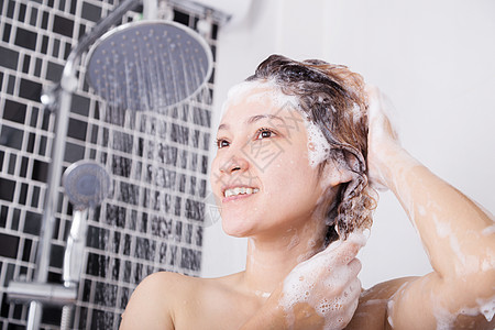 快乐的女子用洗发水洗头和淋浴微笑泡沫身体成人卫生飞溅女性女孩浴室享受图片