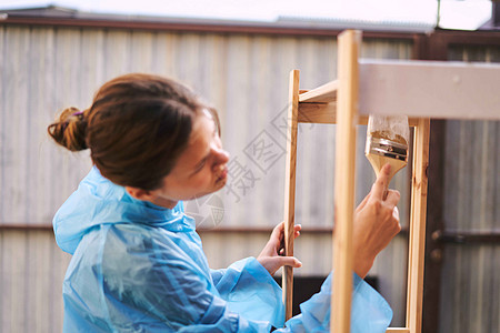 开心的女士 用油漆刷子画木装饰装修画笔画架桌子维修女孩工人木板滚筒木头图片