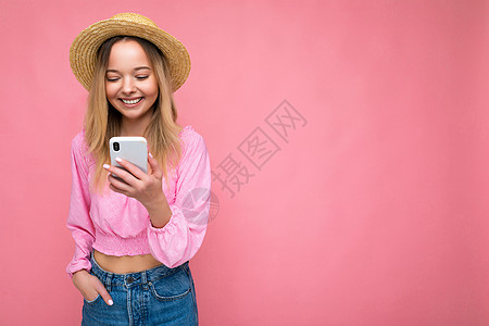 照片拍摄的照片是迷人 正面 漂亮的年轻女性穿着休闲时尚的服装 在背景中与世隔绝 手拿空地 使用手机短信查看智能手机显示屏孩子电话图片