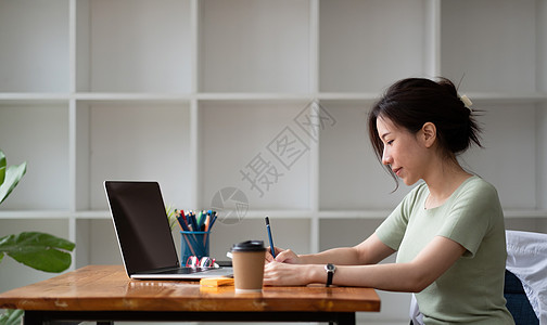 在记事本中工作或在笔记本电脑上学习的女性写作列表的裁剪照片  教育课程或培训 研讨会 在线教育概念技术管理人员职业商务办公室会议图片