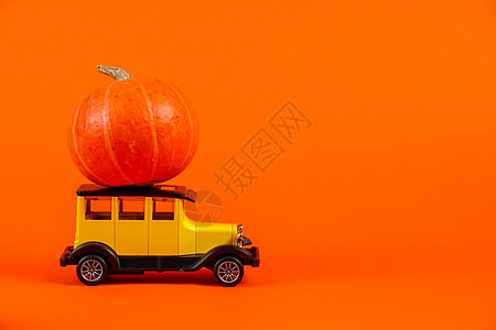 橙色背景上有南瓜的复古玩具车 万圣节和秋收概念图片