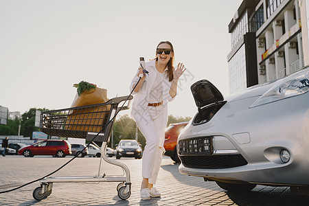 在电加油站用电电车充电的妇女机动性驾驶生态司机太阳收费街道人士电池商务图片