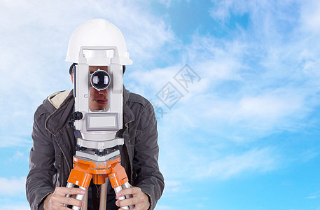 工程工程师 与测量设备合作使用蓝色天空的热闪石定位地形帽子水平建筑工具工作头盔白色男人图片