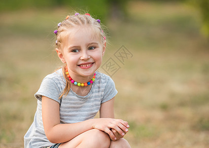 在夏日公园里微笑的小女孩天空童年女孩场地女性太阳幸福晴天草地日落图片