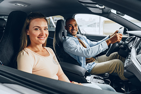 快乐的年轻夫妇在一辆车里四处看 他们准备在汽车店买新车车辆店铺男性微笑消费者夫妻幸福陈列室零售男人图片