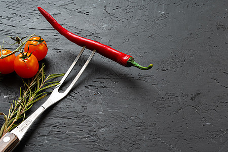 黑石背景的叉子上的红辣椒辣椒厨房蔬菜胡椒烹饪石头银叉节食燃烧植物食物图片