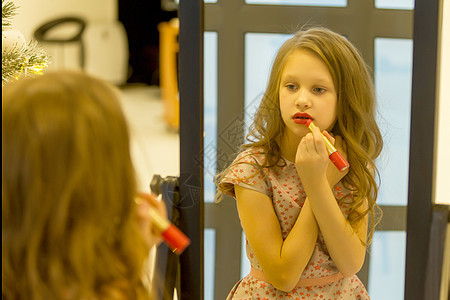 迷人的长海亮女孩在镜子前应用唇膏图片