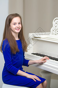 一个十几岁的女孩在弹白色大钢琴手指艺术家键盘艺术旋律音乐家学生钢琴家学习仪器图片