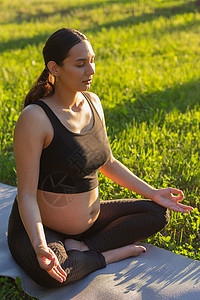 可爱的年轻caucasian孕妇正在冥想 当时她正坐在一个阳光明媚的夏夜草坪上的地毯上坐着日落成人晴天瑜伽生活练习母性运动怀孕喜图片