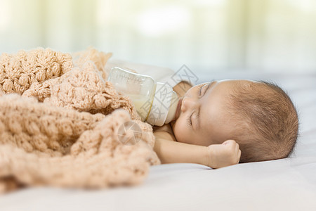 喝瓶装牛奶和睡在床上的婴儿男生睡眠生活说谎瓶子孩子女孩食物新生童年图片