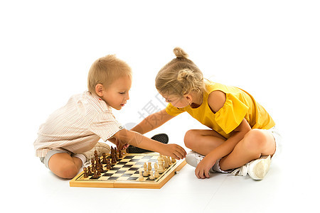 小男孩和小女孩坐在地上下象棋游戏棋盘活动俱乐部男生挑战爱好桌子木板教育图片