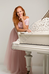 美丽的年轻女子 在白色大钢琴附近琴键手指音乐家艺术家奢华旋律古典音乐音乐音乐会学习图片