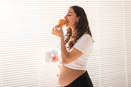 孕妇吃羊角面包和喝咖啡 怀孕假和产假 包括孩子微笑母亲饮食婴儿幸福烘烤父母营养产妇图片