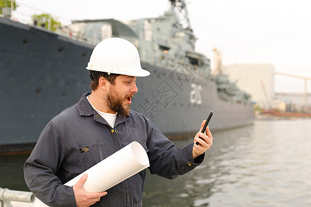 戴头盔的海洋工程师持有甚高频对讲机和背景在船只附近的文件图片