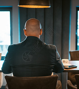 身着昂贵西装的CEO商务人士背影 坐在现代高贵办公室内地的桌子上 秃头男子在笔记本电脑上工作图片