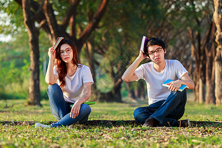 男人和女人坐在公园里看一本书学生闲暇女孩男人花园男性友谊女士专注学习图片