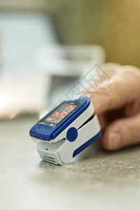 在家里使用指尖血氧计测量人体氧气的人图片