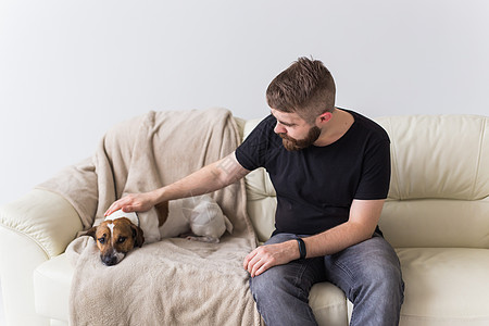 睡沙发上有可爱的狗杰克·罗瑟利帽的男人 宠物和家喻户晓图片