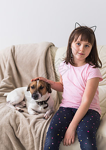 沙发上有可爱的狗杰克罗瑟尔特瑞的女孩 宠物 孩子和家庭概念行动友谊孩子们猎犬房间快乐微笑女性动物乐趣图片