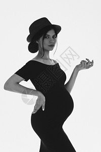 美丽怀孕的年轻女孩肚子戴着帽子和黑色的裙子怀孕了 时尚怀孕 黑与白图片