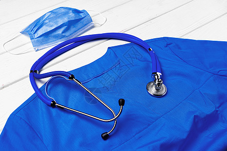白色木质背景上带听诊器和面罩的医生医用制服治疗感染疾病流感药品衣服诊断身体手术卫生图片