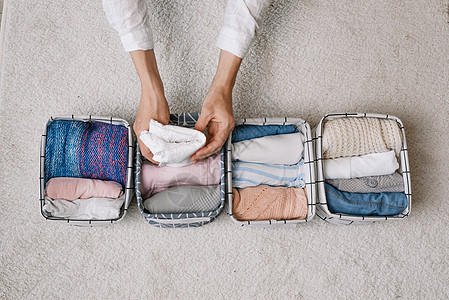 在现代存储系统的帮助下 一位整洁的家庭主妇在进行一般清洁时将物品放入洗衣容器中 顶视图 一个美丽舒适的组织的概念内饰毛巾女士衣柜图片