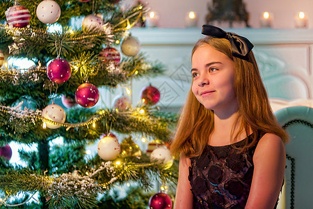 穿着时尚服装的女孩坐在圣诞树前的地板上 笑声花环假期风格童年礼物幸福针叶装饰蜡烛庆典图片