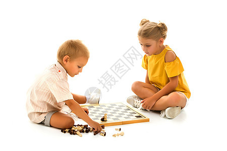小男孩和小女孩坐在地上下象棋教育学校闲暇桌子棋盘玩家乐趣木板游戏胜利图片