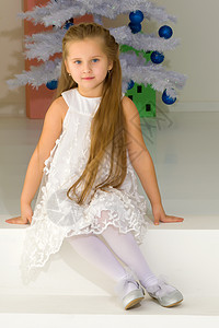 穿着时尚服装的女孩坐在圣诞树前的地板上 笑声庆典幸福快乐家庭假期装饰装潢礼物花环蜡烛图片