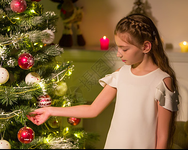 穿着时尚服装的女孩坐在圣诞树前的地板上 笑声假期庆典礼物枞树装饰快乐花环装饰品风格家庭图片